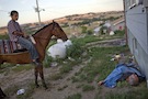 Boy On Horseback Looking At Passed Out Man